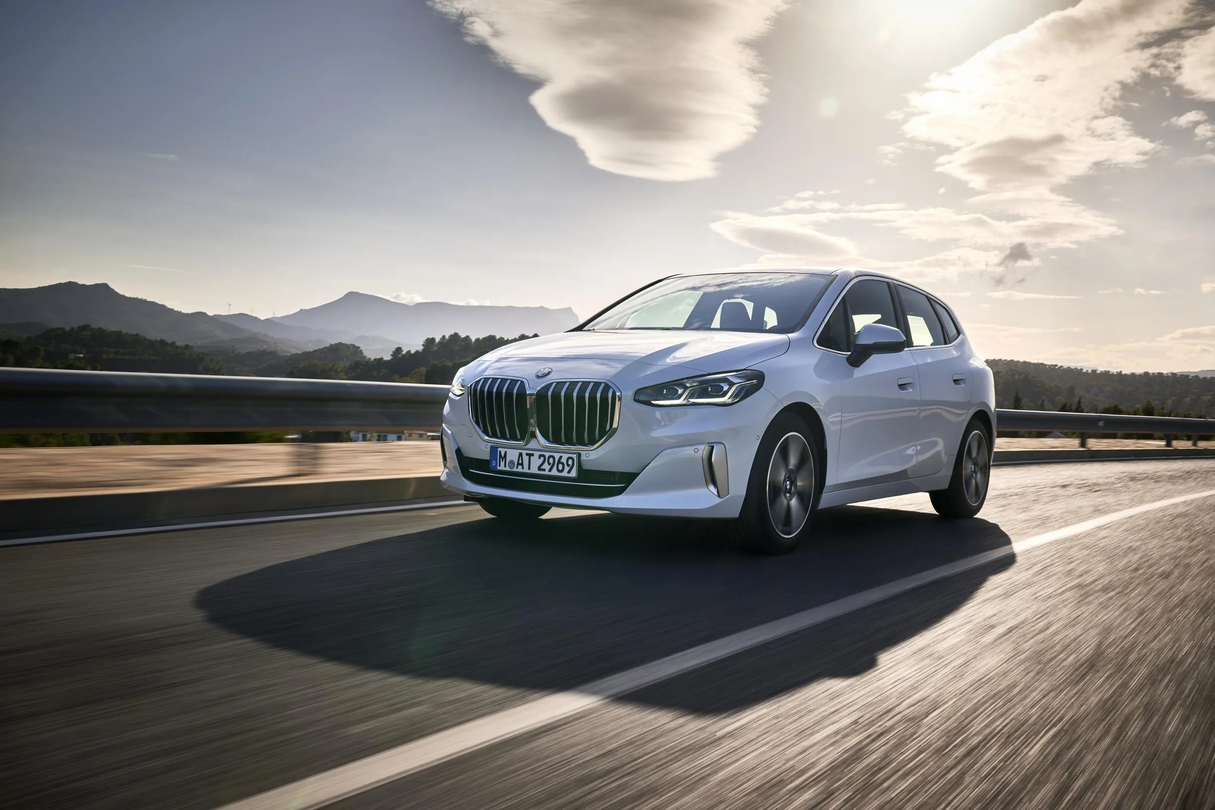 White Bmw Suv Driving on Road with Mountains Behind