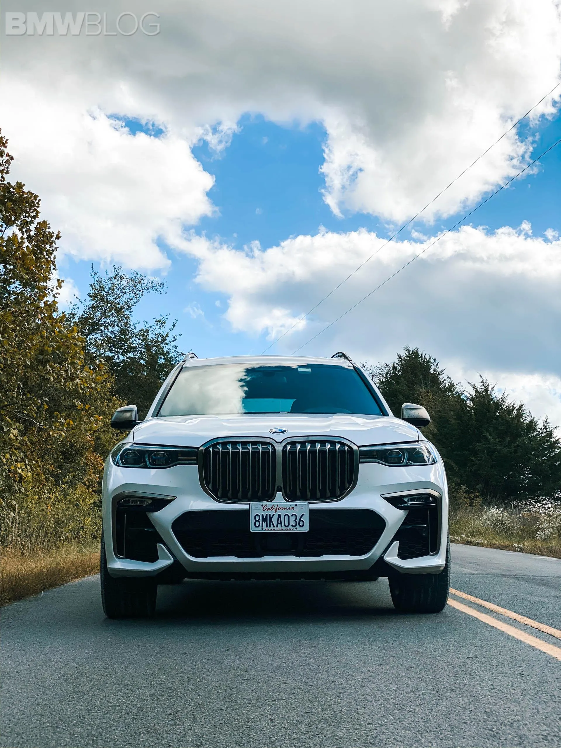 White Bmw Suv Driving Under Blue Sky with Clouds and Trees