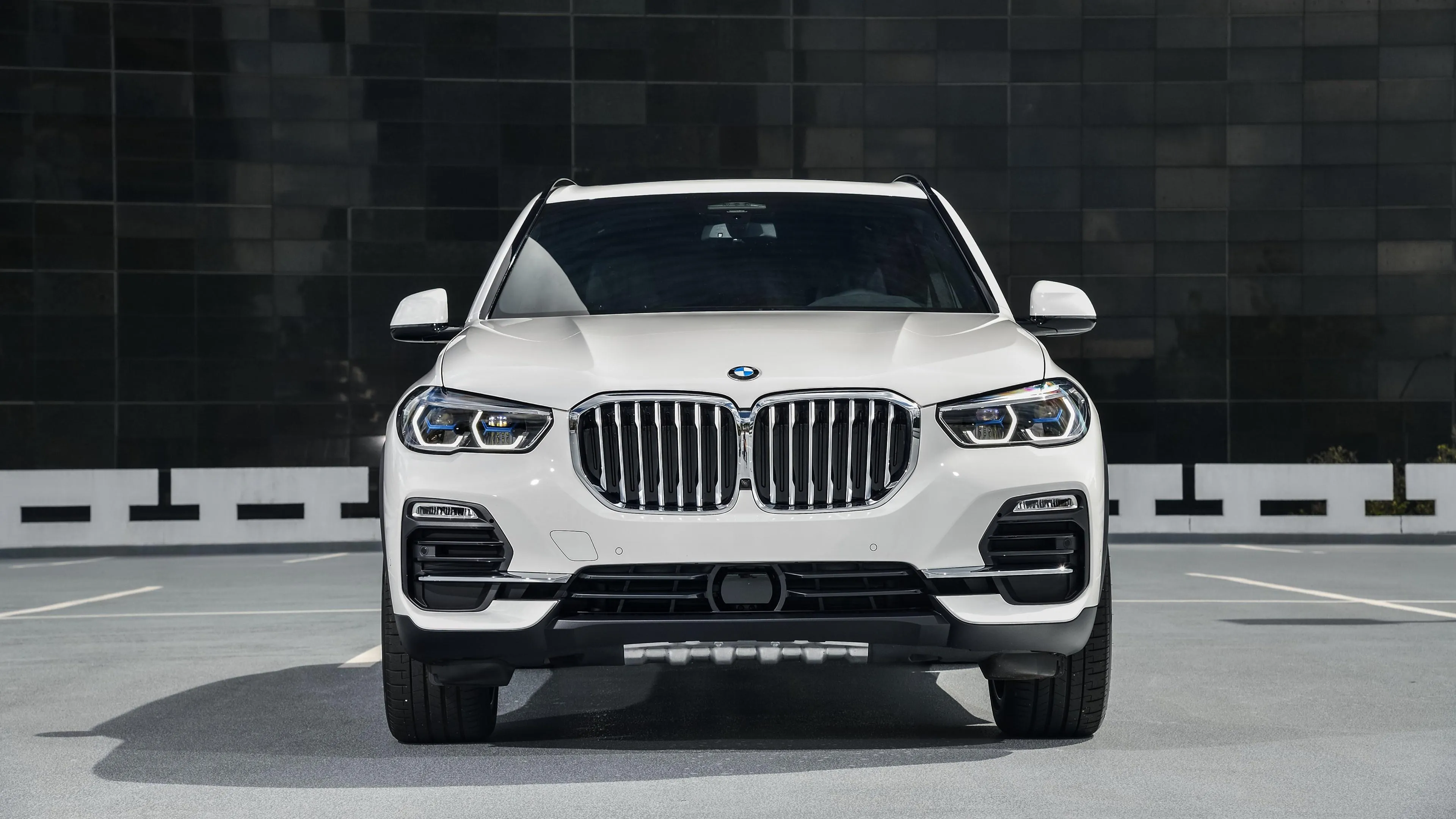 White Bmw Suv Parked in Front of Dark Geometric Wall