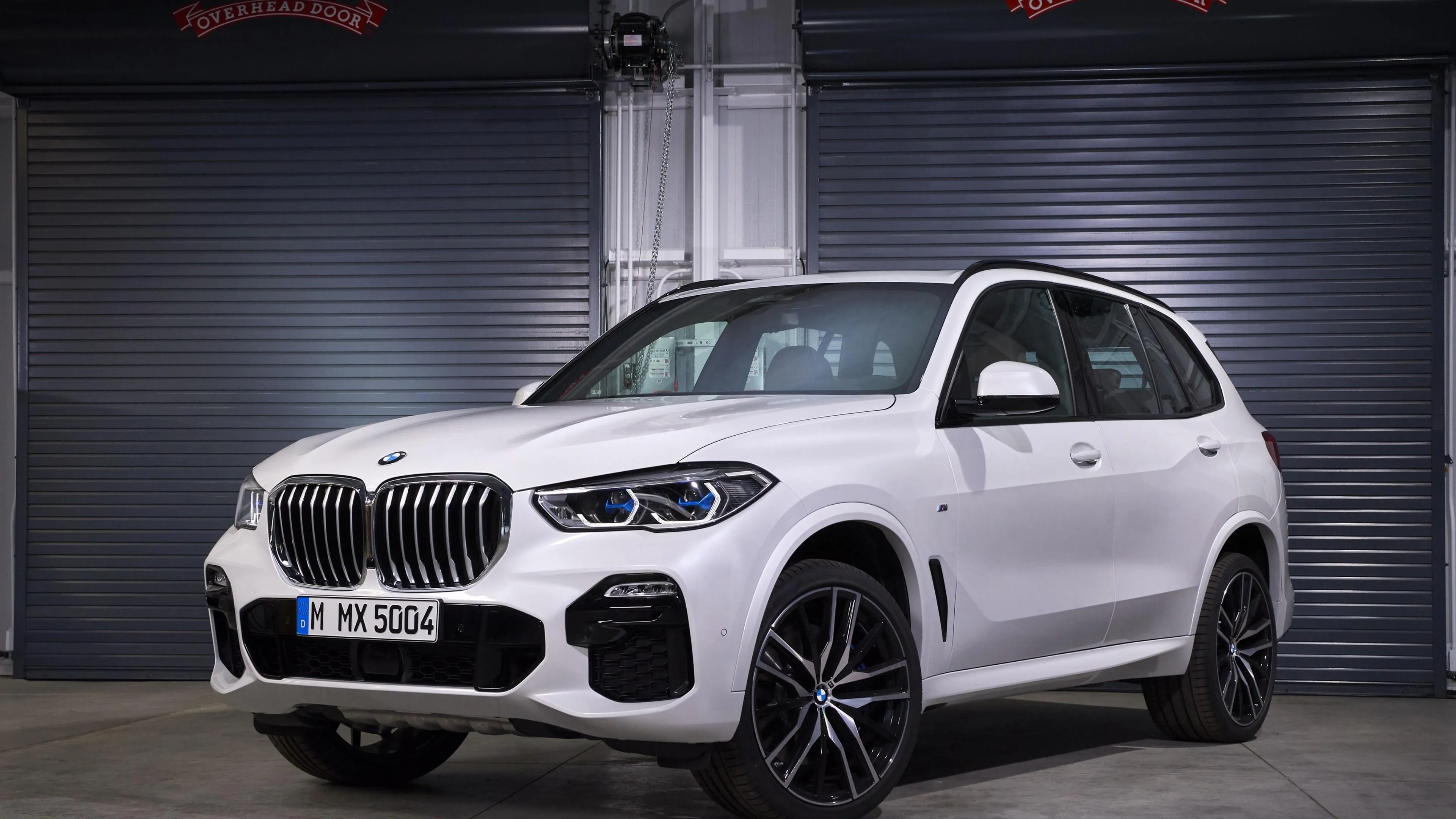 White Bmw Suv Parked Inside a Modern Garage Under Lights