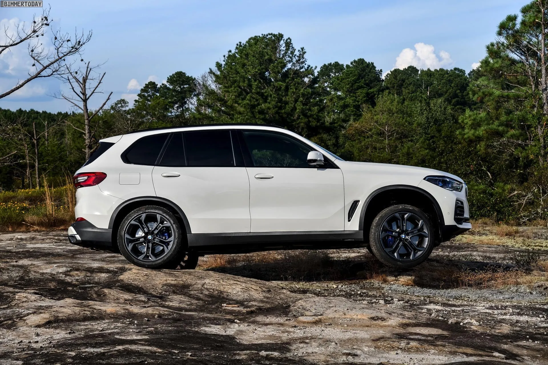 White Bmw Suv Parked on Rocky Terrain with Forest View