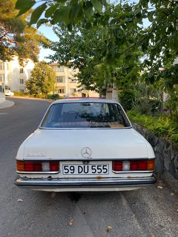 White Classic Mercedes Benz Parked Near Leafy Road