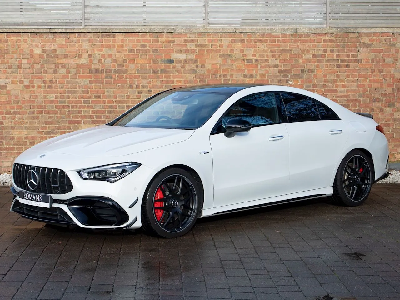 White Mercedes Benz Coupe with Red Brakes on Brick Wall