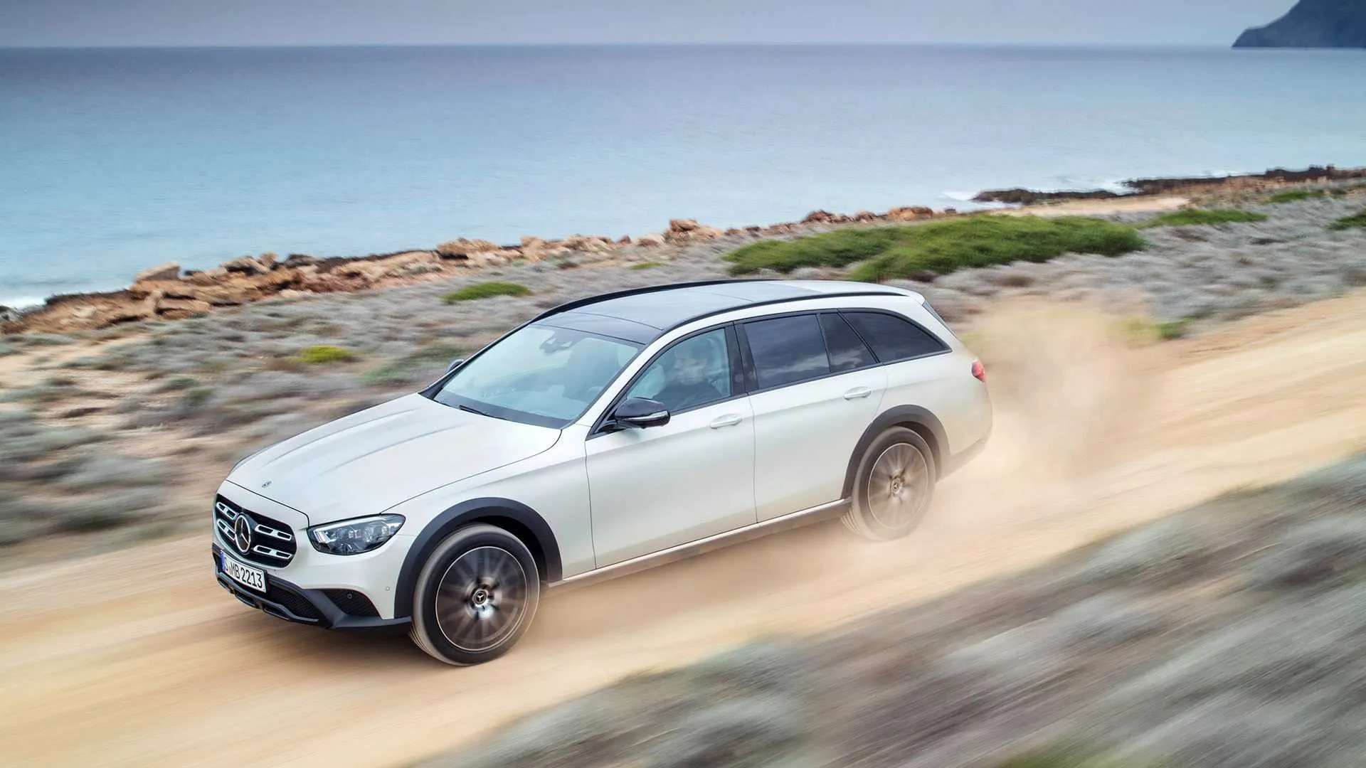White Mercedes Benz Driving on Sandy Road in Coastal Area