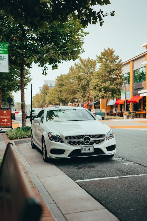 White Mercedes Benz on Street Near Shops and Trees image