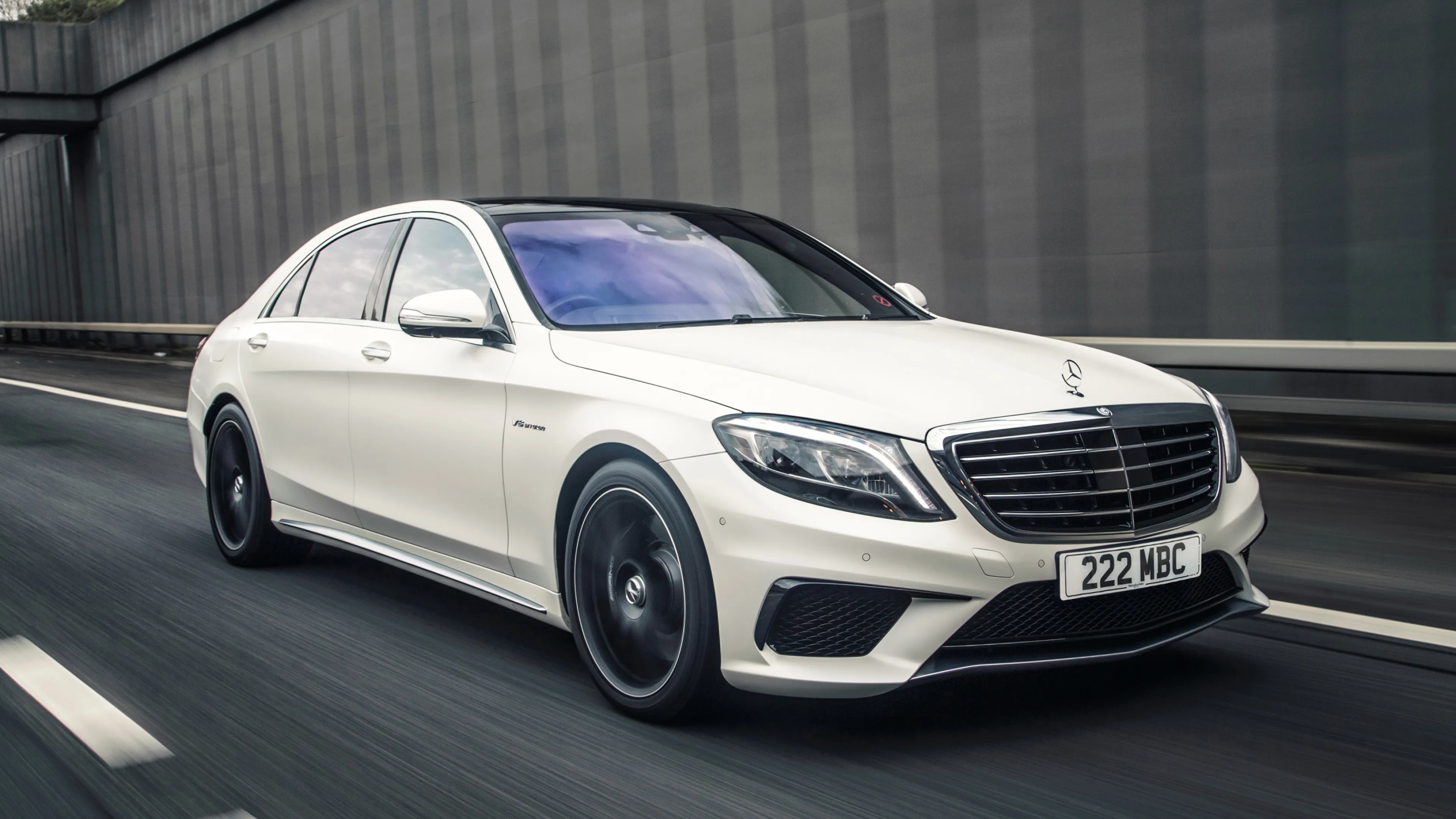 White Mercedes Benz Sedan Driving Along Modern Buildings
