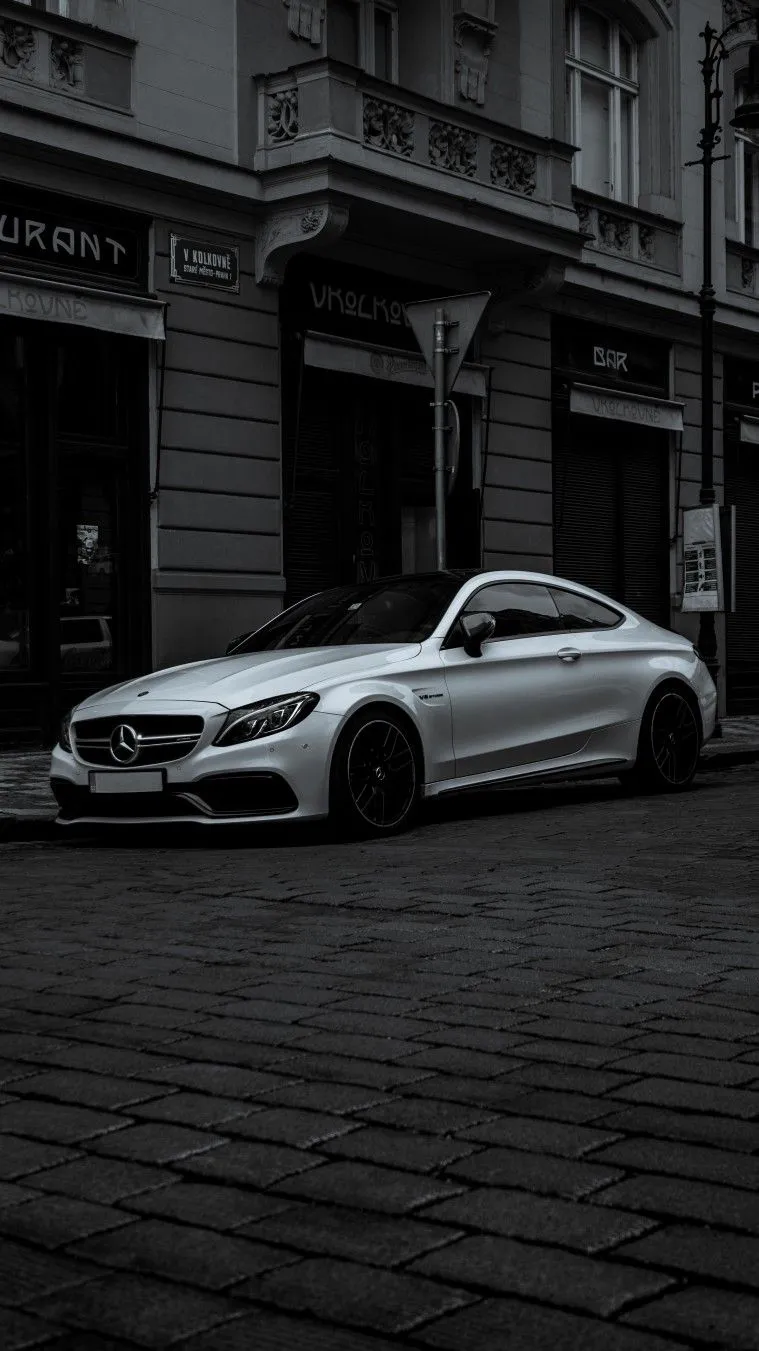 White Mercedes Coupe Parked on Cobblestone City Street