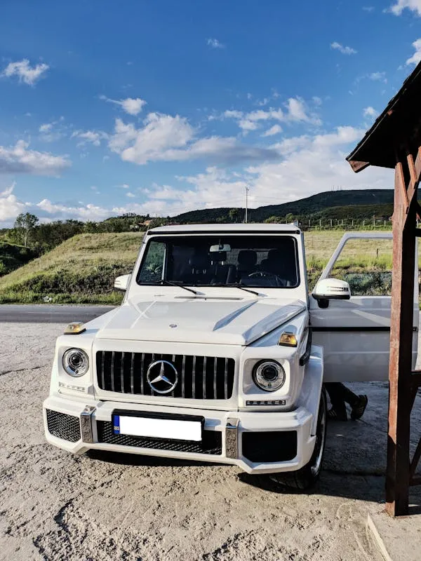 White Mercedes G Wagon Parked Beside Wooden Cabin Wallpaper