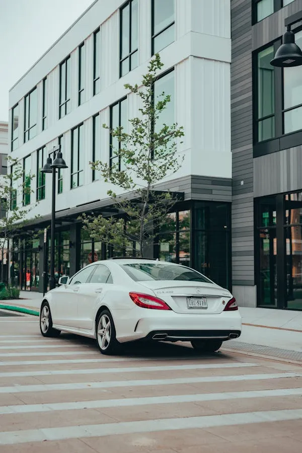 White Mercedes parked near modern glass office buildings