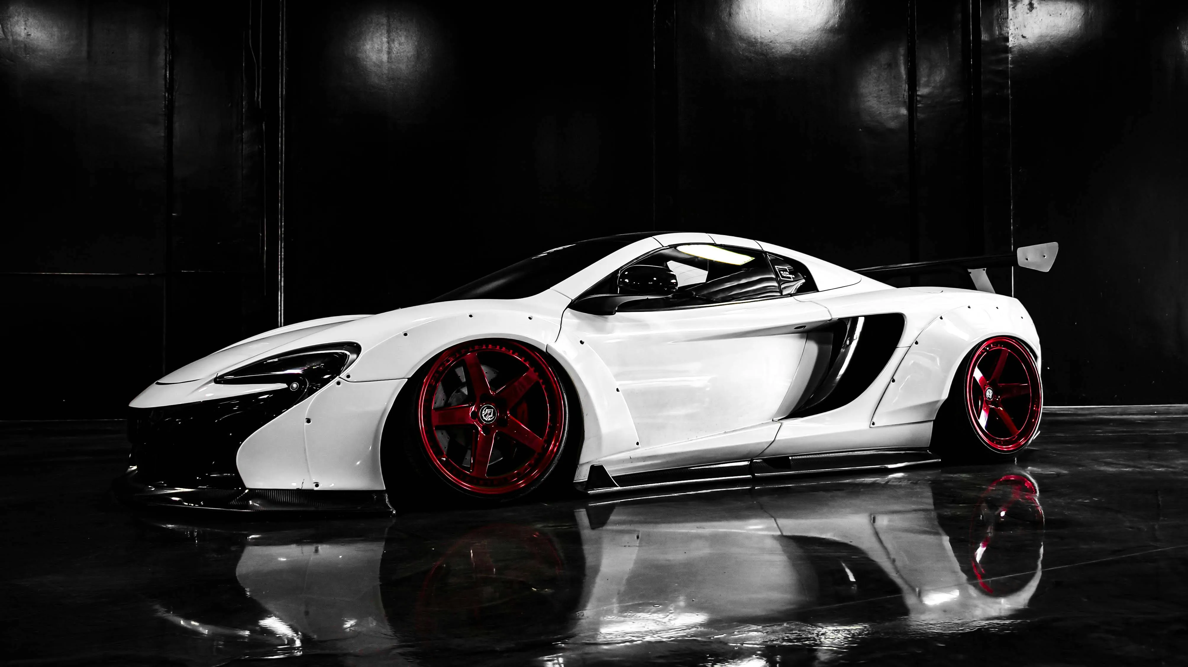 White Sports Car with Red Rims Under Studio Lighting