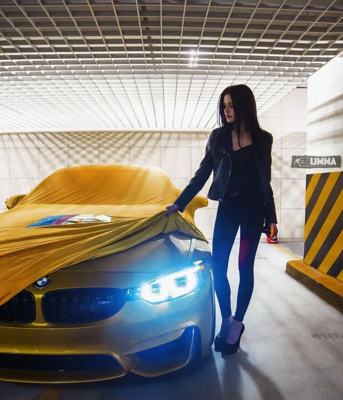 Woman Standing By a Yellow Bmw with Blue Headlights On