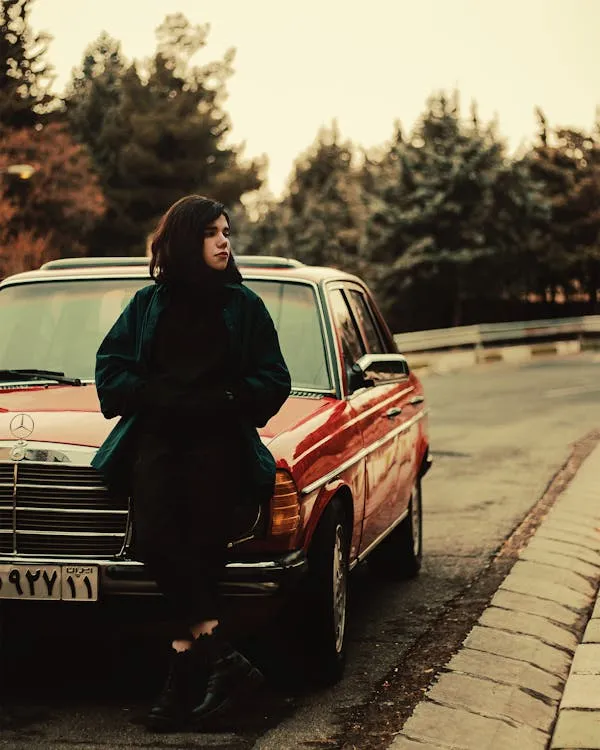 Woman standing next to a vintage Mercedes car on street
