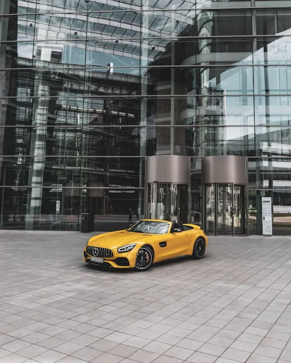 Yellow Mercedes Benz Parked at Modern Glass Building